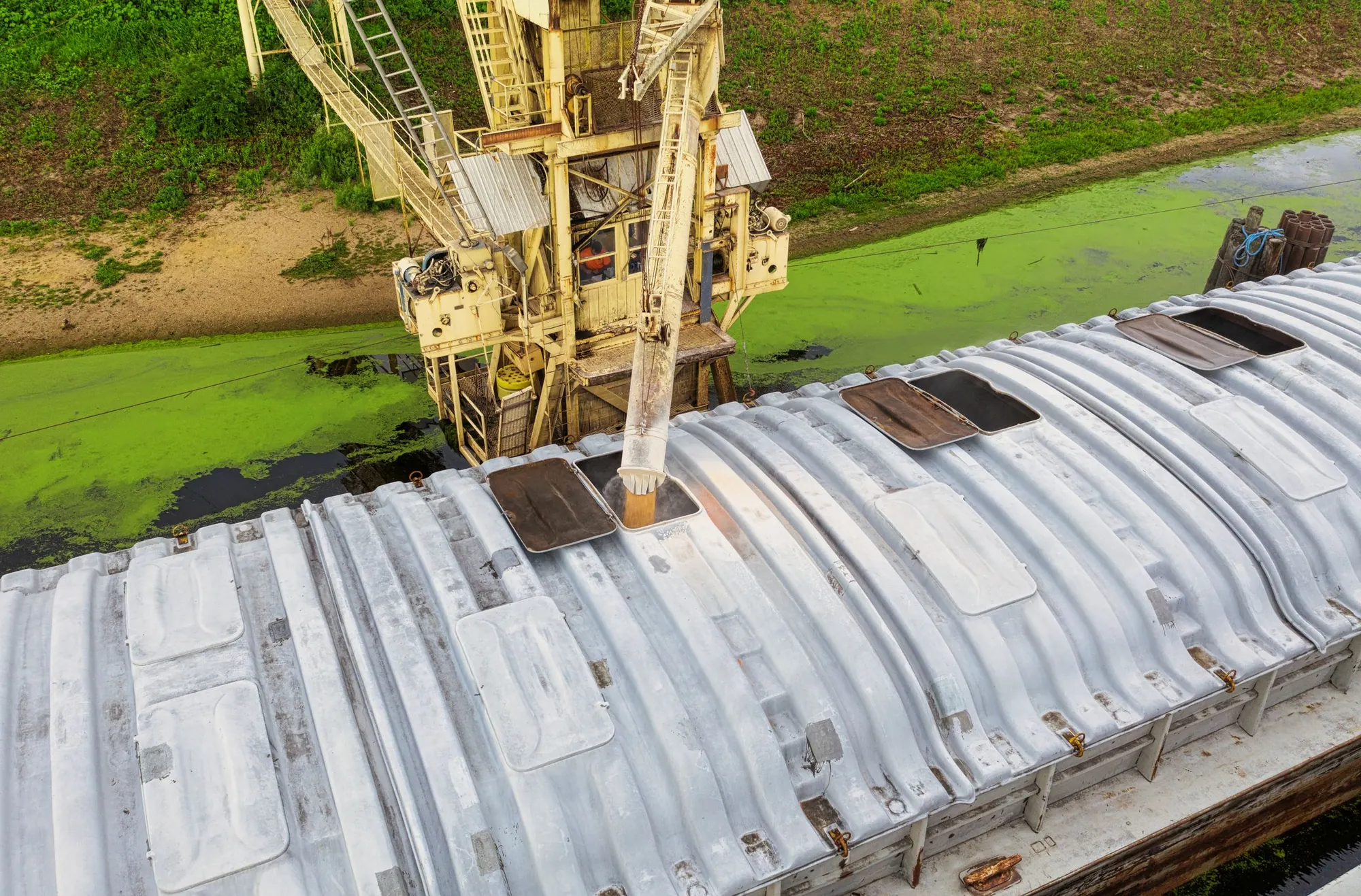 Grain barge being loaded at a river terminal, aerial view